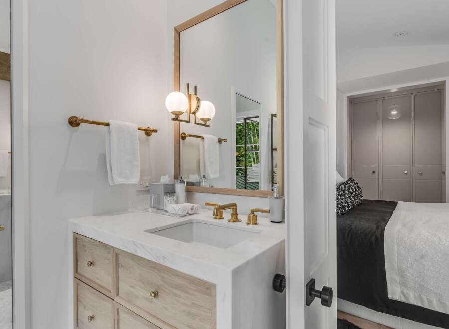 Experience modern luxury in this stunning bathroom featuring a sleek marble vanity with warm wood cabinetry and elegant brass fixtures.