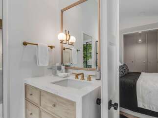 Experience modern luxury in this stunning bathroom featuring a sleek marble vanity with warm wood cabinetry and elegant brass fixtures.