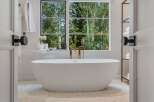 Indulge in ultimate relaxation in this luxurious bathroom, featuring a stunning freestanding bathtub with a modern gold faucet.
