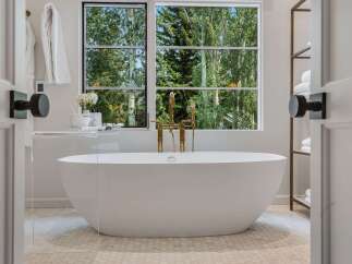 Indulge in ultimate relaxation in this luxurious bathroom, featuring a stunning freestanding bathtub with a modern gold faucet.