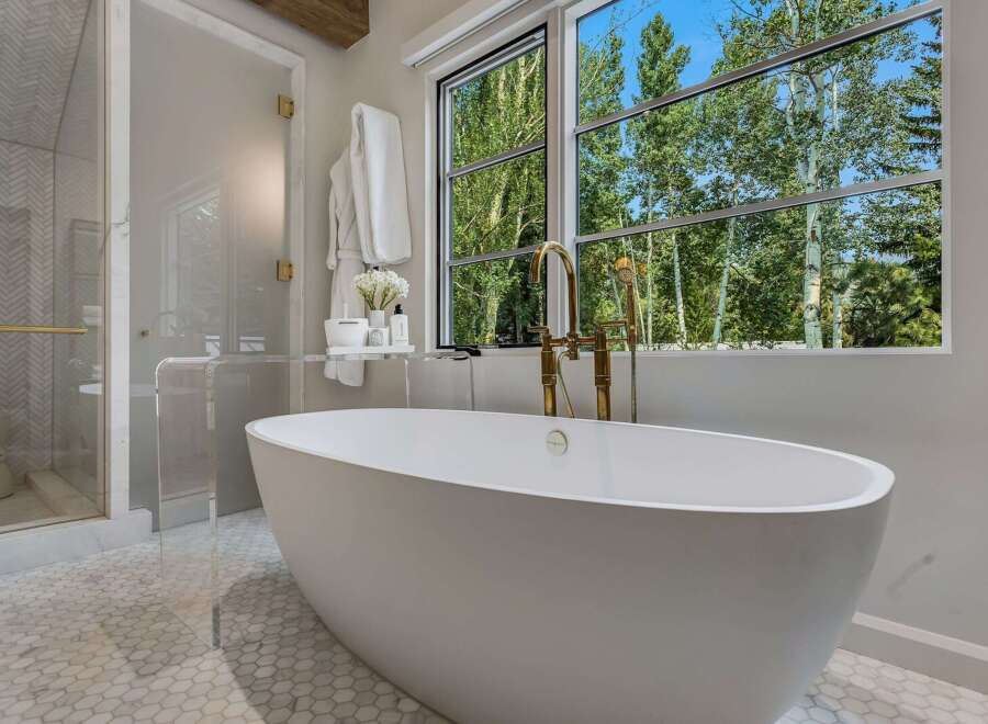 Indulge in luxury with this stunning bathroom featuring a freestanding soaking tub and a separate glass-enclosed shower.
