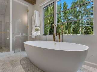 Indulge in luxury with this stunning bathroom featuring a freestanding soaking tub and a separate glass-enclosed shower.