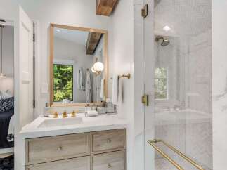 Experience modern luxury in this stunning bathroom, featuring a sleek vanity with marble countertops and warm wood cabinetry.