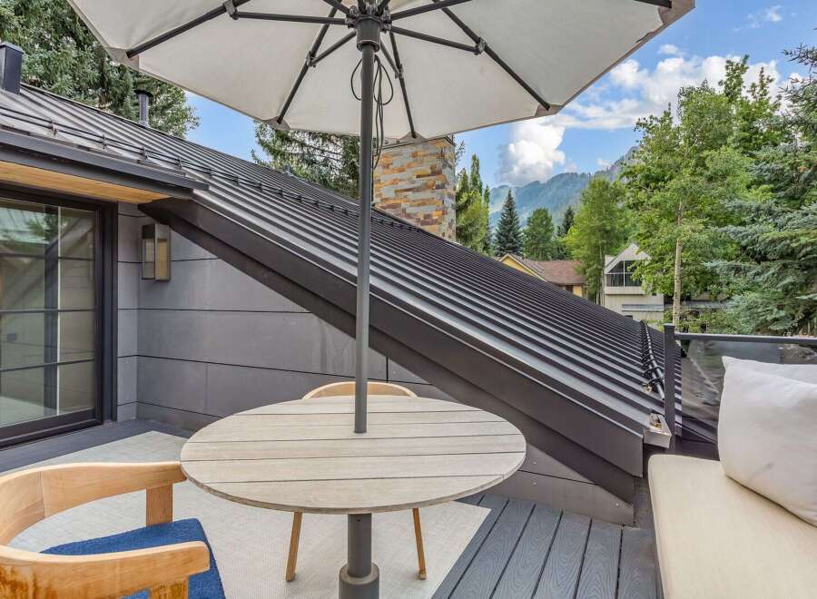 Enjoy breathtaking mountain views from this stunning outdoor living space, complete with a modern metal roof and a cozy seating area.