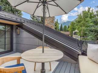 Enjoy breathtaking mountain views from this stunning outdoor living space, complete with a modern metal roof and a cozy seating area.