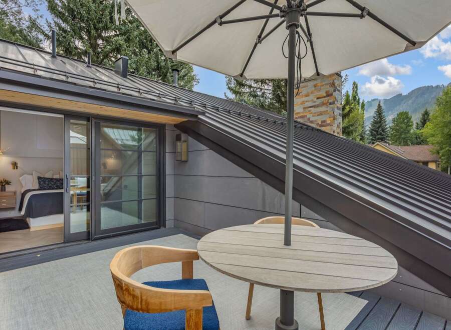 Enjoy breathtaking mountain views from this private balcony, featuring a comfortable seating area with a round dining table and umbrella.