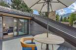 Enjoy breathtaking mountain views from this private balcony, featuring a comfortable seating area with a round dining table and umbrella.