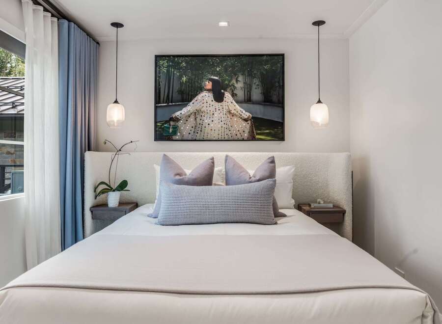 Experience modern comfort in this serene bedroom, featuring a plush, textured headboard and a large, captivating artwork above the bed.