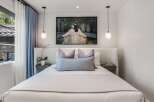 Experience modern comfort in this serene bedroom, featuring a plush, textured headboard and a large, captivating artwork above the bed.