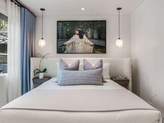 Experience modern comfort in this serene bedroom, featuring a plush, textured headboard and a large, captivating artwork above the bed.