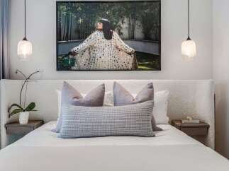 Experience luxurious comfort in this master bedroom, featuring a plush, textured headboard and a king-sized bed adorned with elegant throw pillows.