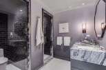 Experience modern luxury in this stunning bathroom, featuring a sleek glass-enclosed shower with dark subway tiles and a sophisticated marble vanity.