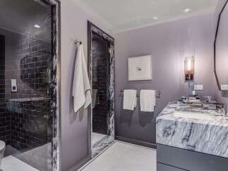 Experience modern luxury in this stunning bathroom, featuring a sleek glass-enclosed shower with dark subway tiles and a sophisticated marble vanity.