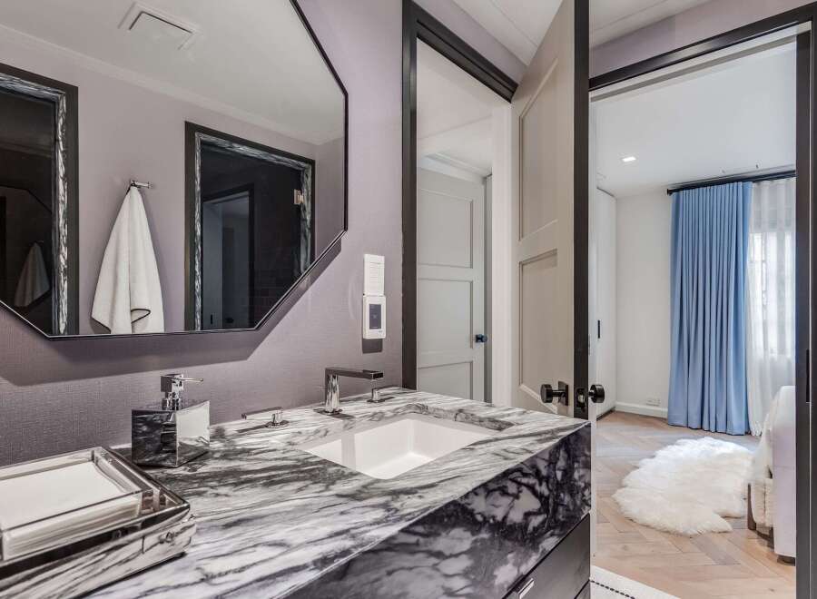 Experience luxury in this modern bathroom, featuring a striking marble vanity with a sleek undermount sink and polished chrome fixtures.