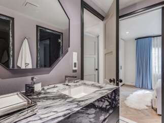 Experience luxury in this modern bathroom, featuring a striking marble vanity with a sleek undermount sink and polished chrome fixtures.