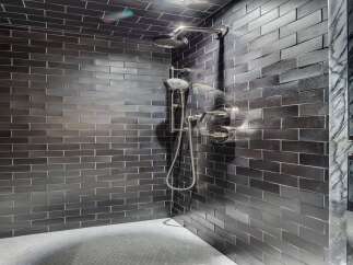 Experience modern luxury in this stunning shower featuring sleek, dark subway tiles that create a sophisticated ambiance.