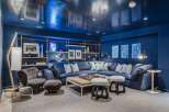 Experience ultimate relaxation in this luxurious media room, featuring a deep navy palette and a plush sectional sofa perfect for movie nights.