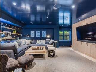 Experience ultimate relaxation in this sophisticated basement lounge, featuring a plush sectional sofa perfect for movie nights.