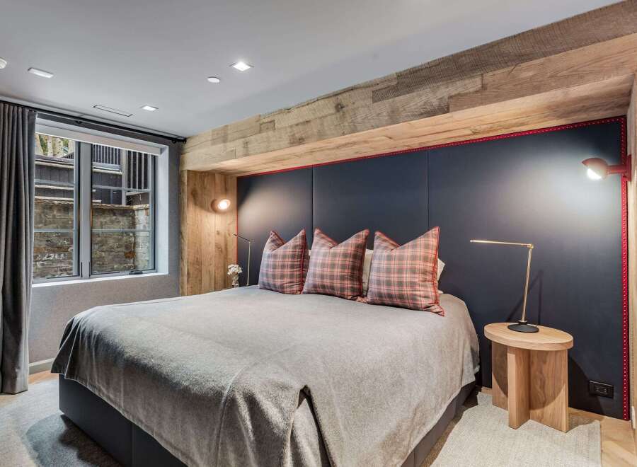 Experience ultimate comfort in this luxurious bedroom, featuring a plush king-size bed adorned with stylish plaid pillows.