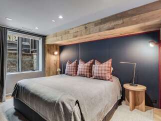 Experience ultimate comfort in this luxurious bedroom, featuring a plush king-size bed adorned with stylish plaid pillows.