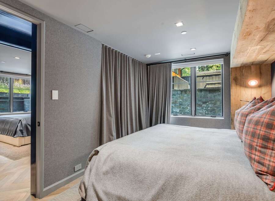 Experience ultimate comfort in this stylish bedroom, featuring a plush bed adorned with plaid accent pillows and a soft, textured blanket.