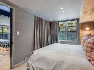 Experience ultimate comfort in this stylish bedroom, featuring a plush bed adorned with plaid accent pillows and a soft, textured blanket.