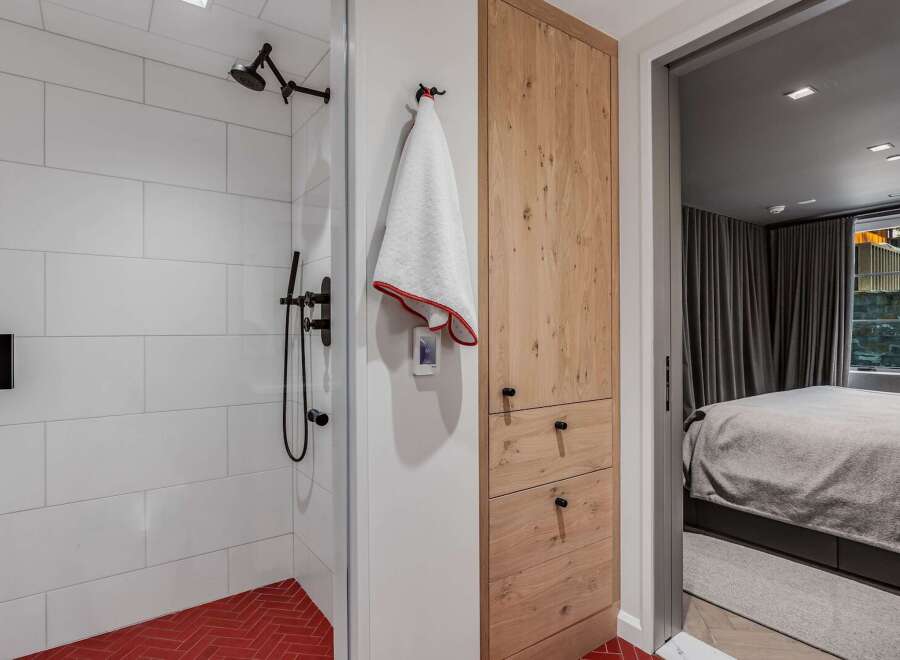 Experience modern comfort in this stylish bathroom featuring a sleek walk-in shower with white subway tiles and a vibrant red herringbone floor.