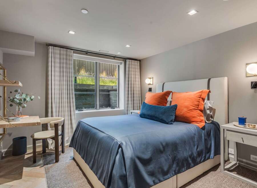 This modern bedroom features a comfortable queen-size bed with a navy blue duvet and vibrant orange accent pillows, creating a cozy and stylish retreat.