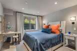 This modern bedroom features a comfortable queen-size bed with a navy blue duvet and vibrant orange accent pillows, creating a cozy and stylish retreat.