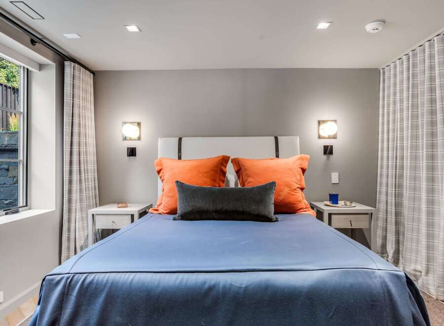 Experience comfort and style in this inviting bedroom, featuring a plush king-sized bed adorned with vibrant orange and charcoal accent pillows.
