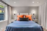 Experience comfort and style in this inviting bedroom, featuring a plush king-sized bed adorned with vibrant orange and charcoal accent pillows.