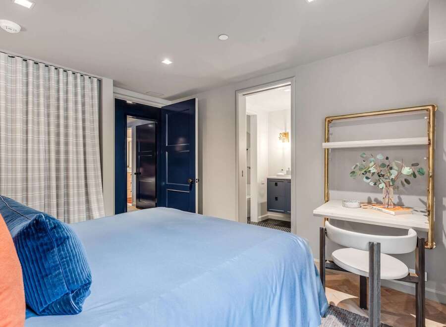This inviting bedroom features a comfortable bed with plush blue and orange accent pillows, complemented by elegant plaid curtains.