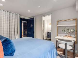 This inviting bedroom features a comfortable bed with plush blue and orange accent pillows, complemented by elegant plaid curtains.