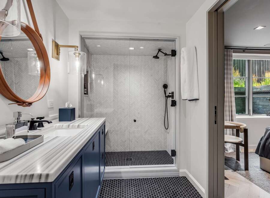Experience modern luxury in this stunning bathroom featuring a sleek vanity with marble countertops and a deep blue cabinet.