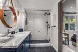 Experience modern luxury in this stunning bathroom featuring a sleek vanity with marble countertops and a deep blue cabinet.
