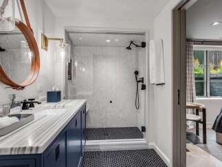 Experience modern luxury in this stunning bathroom featuring a sleek vanity with marble countertops and a deep blue cabinet.