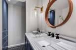 This modern bathroom features a sleek white undermount sink set into a stunning marble countertop with dark blue cabinetry below.