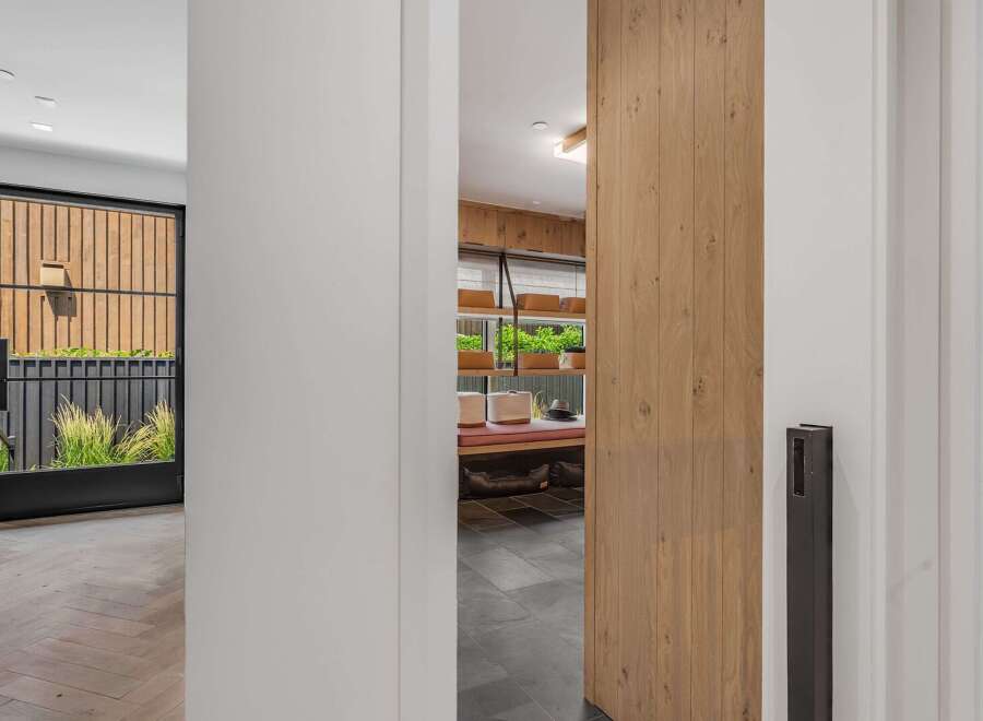 Step into a modern entryway featuring a striking wood-paneled accent wall and a sleek black door leading to an outdoor oasis.