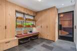 Discover this beautifully designed mudroom featuring custom light wood cabinetry for ample storage and a built-in bench with a comfortable cushion.