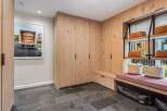 This modern entryway features a custom built-in wood cabinet system with ample storage and a comfortable bench seating area.
