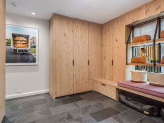 This modern entryway features a custom built-in wood cabinet system with ample storage and a comfortable bench seating area.