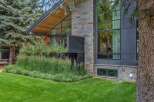 Experience modern luxury in this stunning home, featuring a striking facade of natural stone and dark metal paneling.