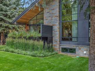 Experience modern luxury in this stunning home, featuring a striking facade of natural stone and dark metal paneling.