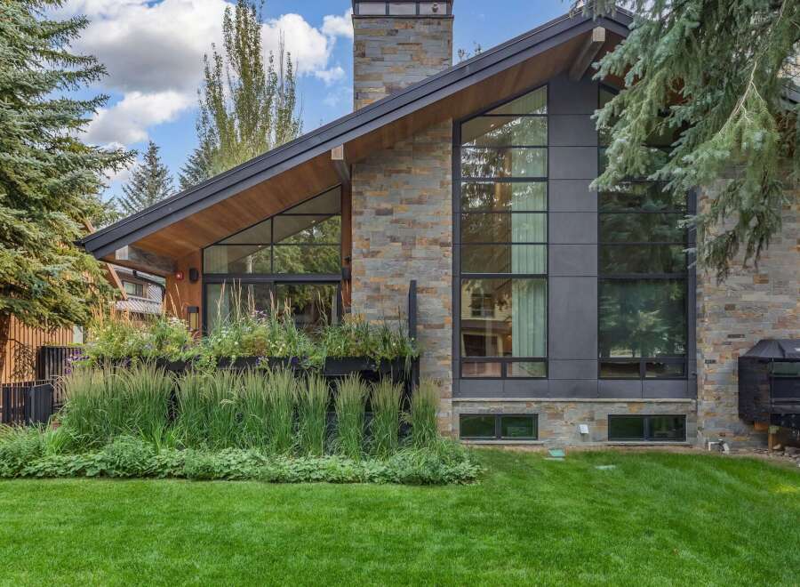Experience modern luxury in this stunning home featuring a striking stone and dark metal exterior.