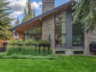 Experience modern luxury in this stunning home featuring a striking stone and dark metal exterior.