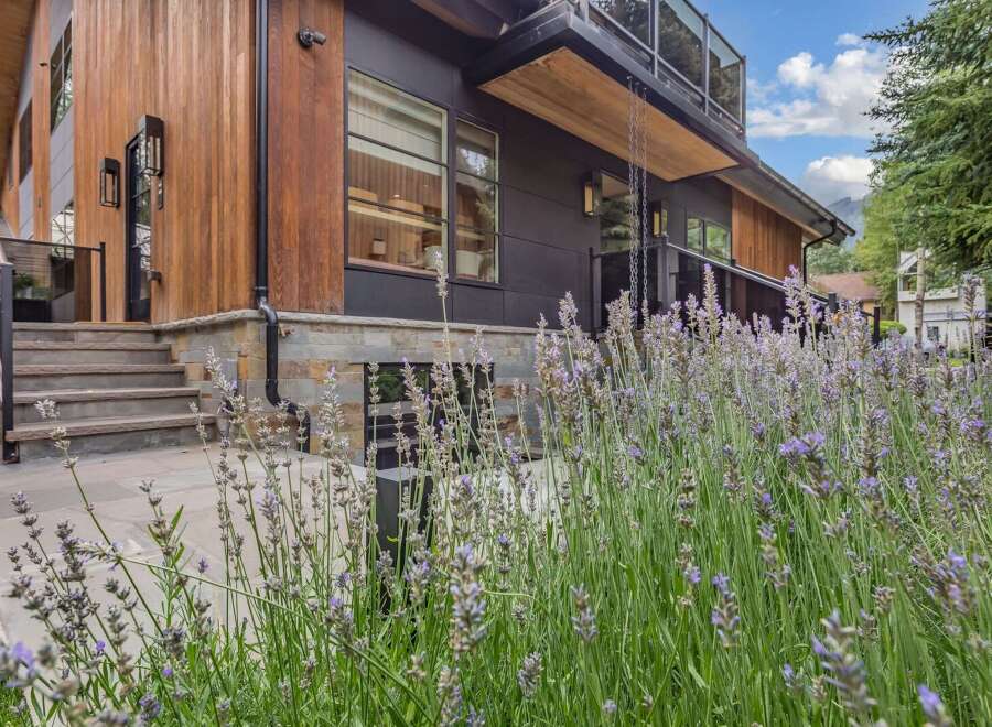 Experience modern luxury in this stunning home featuring warm wood accents and sleek dark siding.