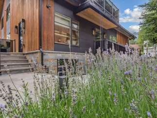 Experience modern luxury in this stunning home featuring warm wood accents and sleek dark siding.