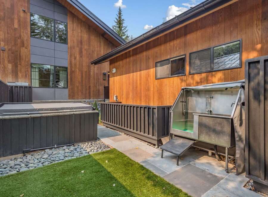 Experience outdoor luxury with this property's modern amenities, including a covered hot tub perfect for relaxation and a professional-grade outdoor dog grooming station.
