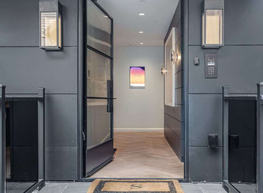 Step into a modern entryway featuring a sleek glass door and contemporary exterior lighting.