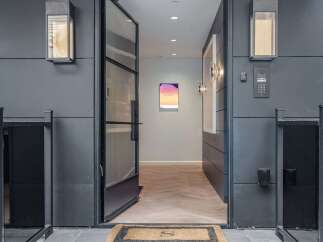 Step into a modern entryway featuring a sleek glass door and contemporary exterior lighting.